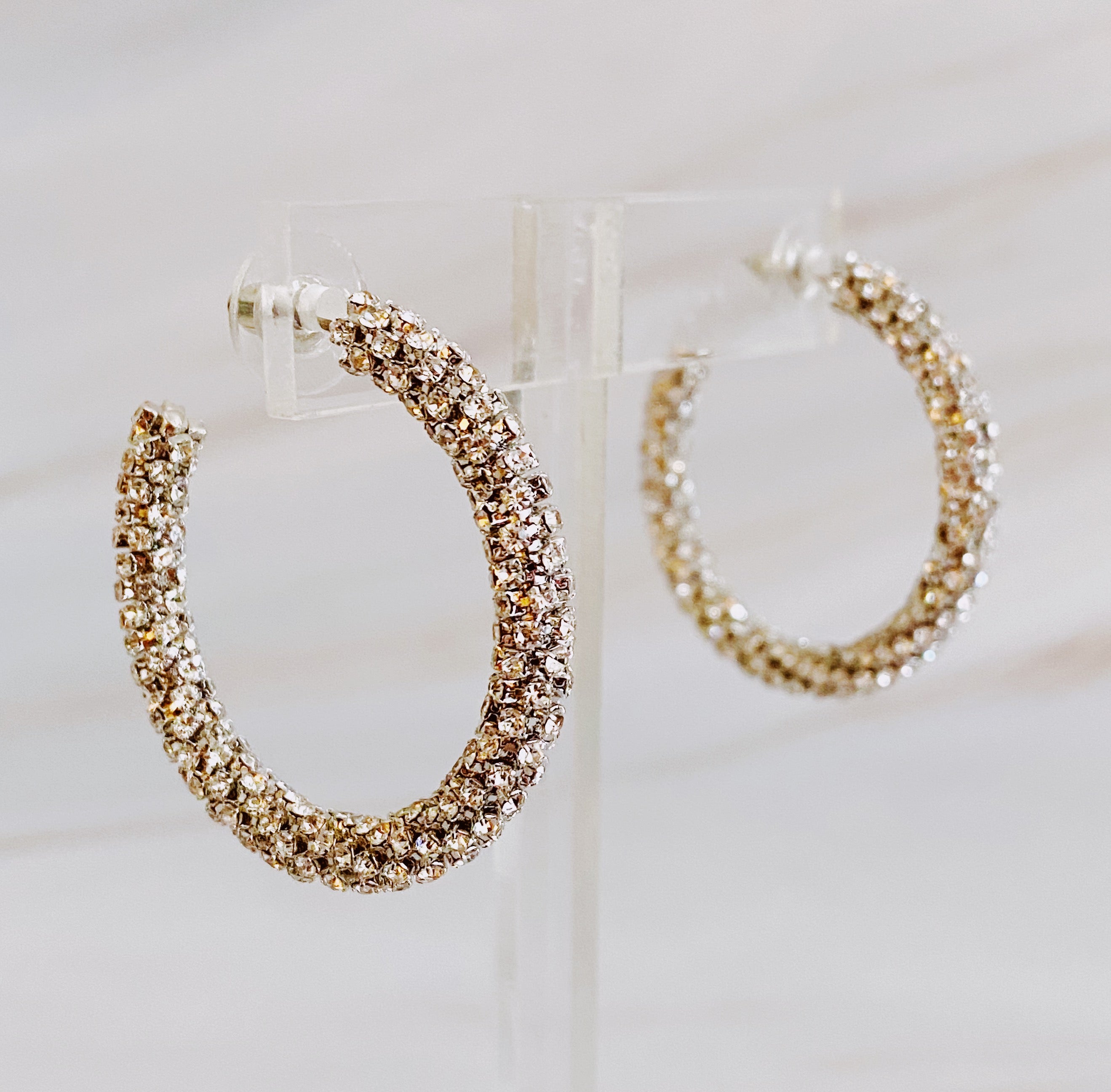 A pair of Wrapped In Shine Hoop Earrings featuring sparkling crystals on a classic hoop design, showcasing elegance and style.