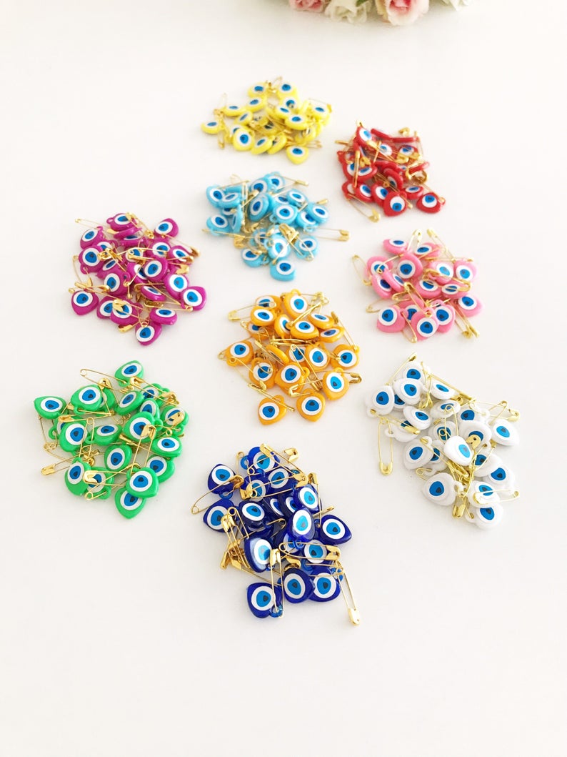 A collection of yellow evil eye beads shaped like hearts, featuring tiny evil eye stickers, displayed on a white background.