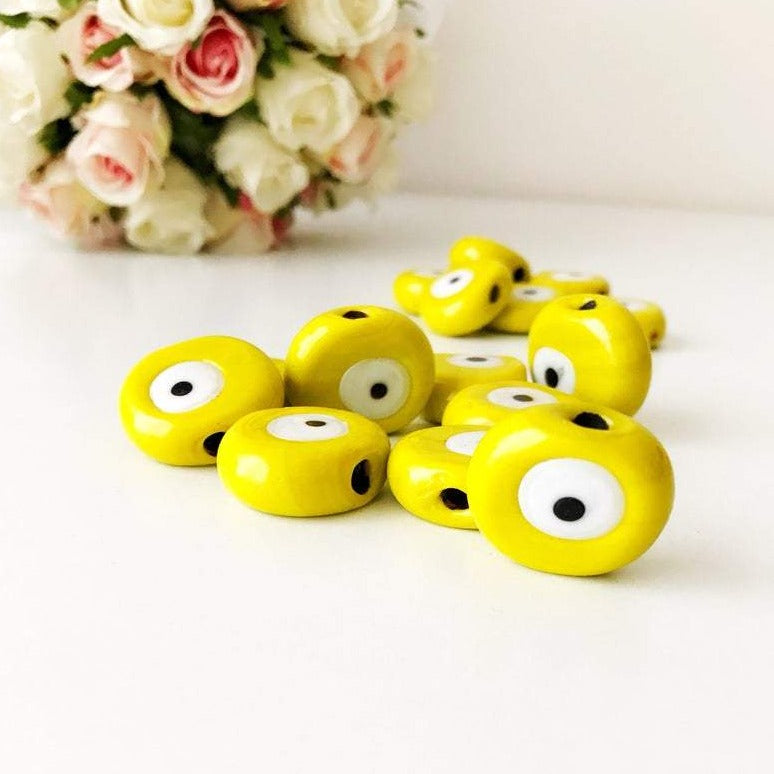 Five handmade yellow Murano glass evil eye beads, each 26mm, showcasing intricate designs and vibrant color.