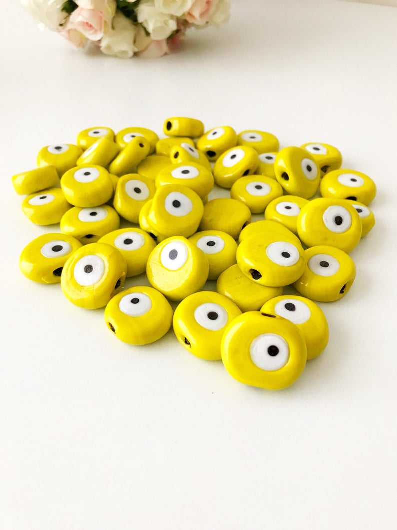 Five handmade yellow Murano glass evil eye beads, each 26mm, showcasing intricate designs and vibrant color.