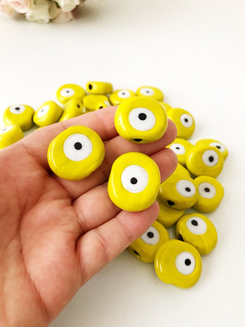 Five handmade yellow Murano glass evil eye beads, each 26mm, showcasing intricate designs and vibrant color.