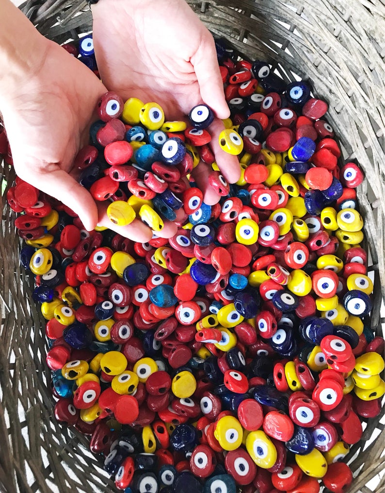 Five handmade yellow Murano glass evil eye beads, each 26mm, showcasing intricate designs and vibrant color.