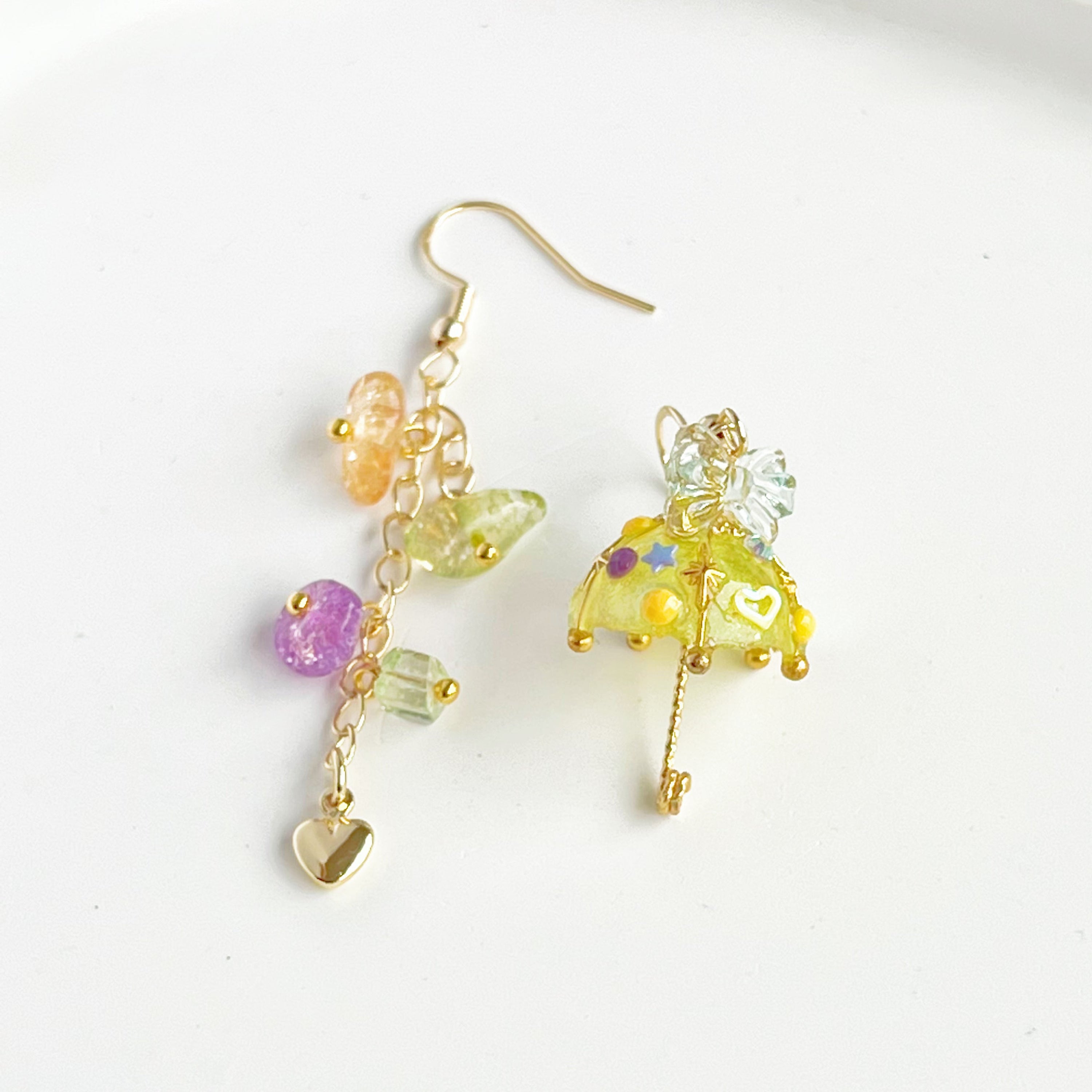 A pair of handmade yellow umbrella drop earrings adorned with colorful rainbow stones, showcasing a unique mismatch design.