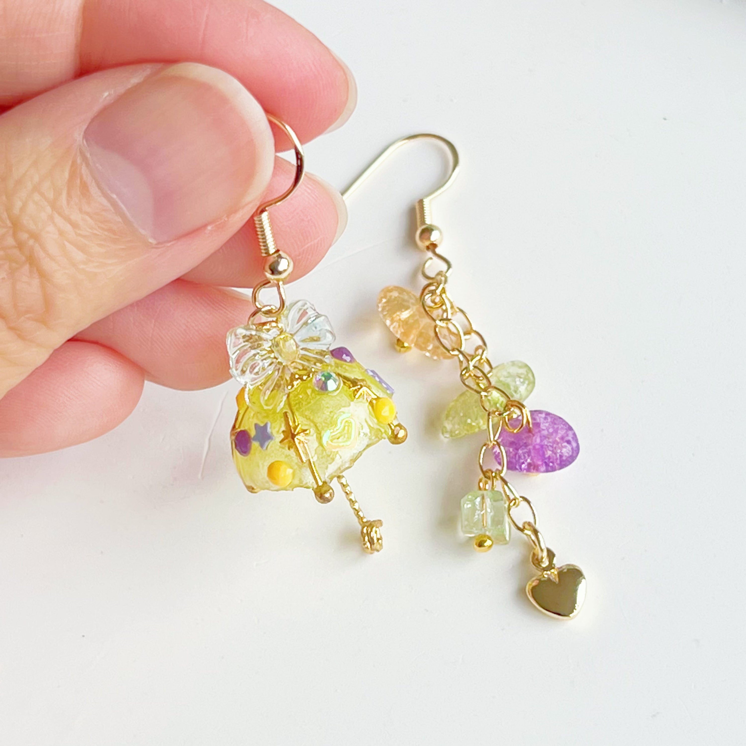 A pair of handmade yellow umbrella drop earrings adorned with colorful rainbow stones, showcasing a unique mismatch design.