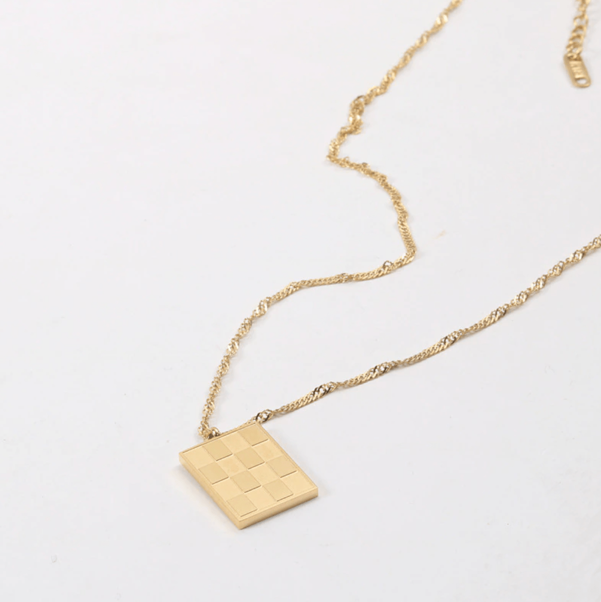 Zeno Checkerboard Gold Pendant Necklace featuring an 18K gold paved pendant and twist rope chain, elegantly displayed on a neutral background.