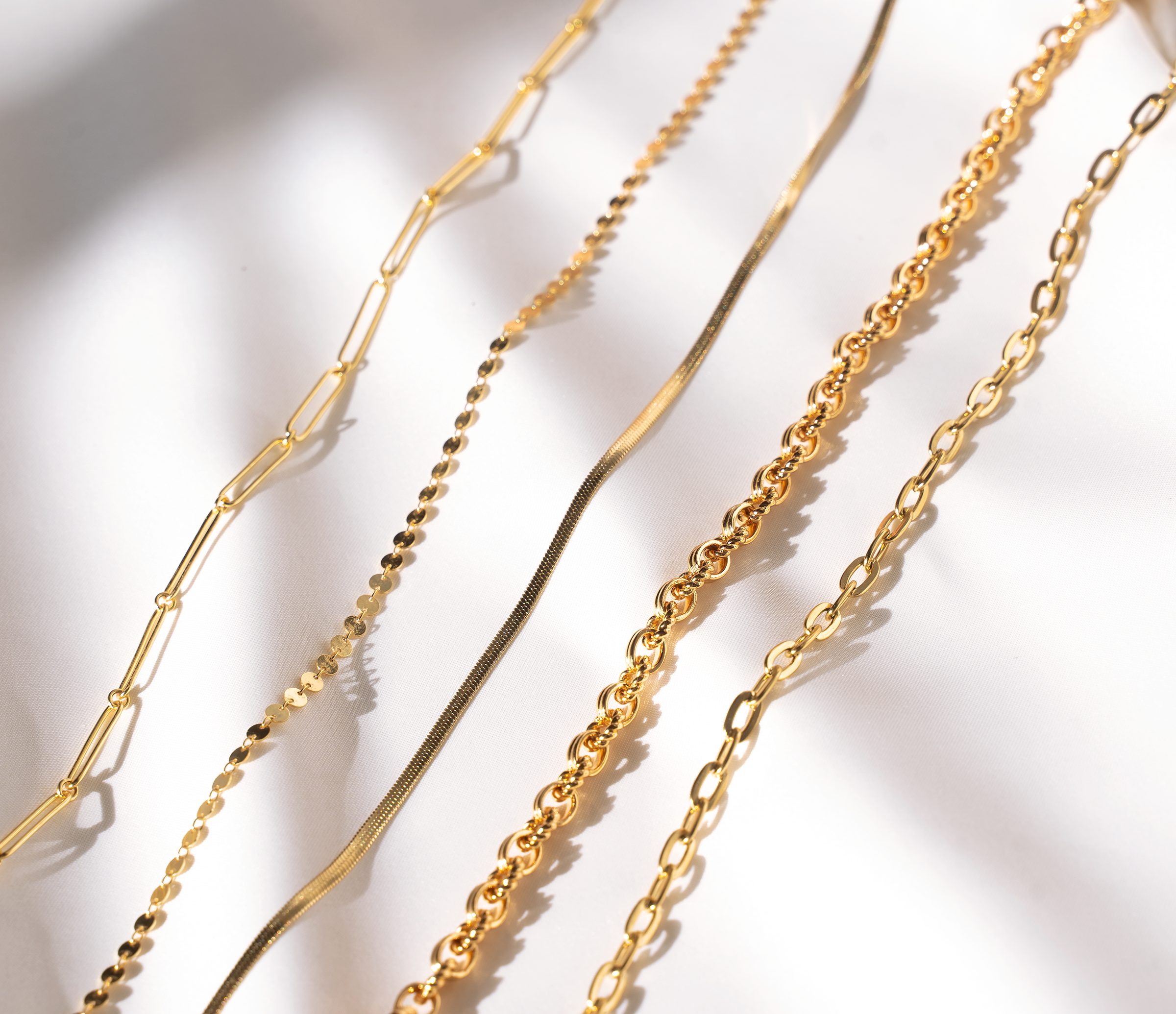 ZIA Snake Chain featuring a classic herringbone link design in 14K gold plating, elegantly laying flat on a collarbone.