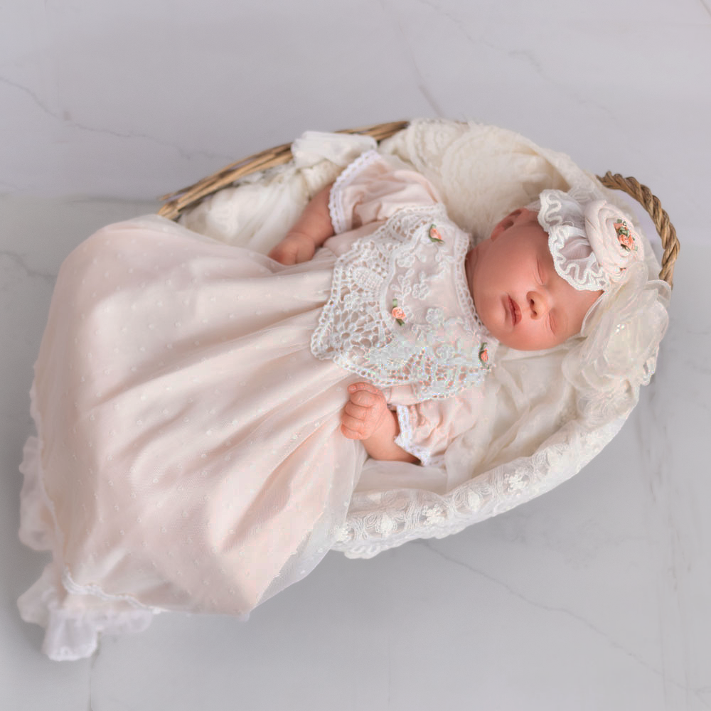 A beautiful pastel peach baby gown adorned with delicate rose embellishments, perfect for special occasions.