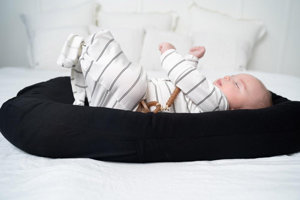 A cozy COCOON & COVER baby lounger in a soft color, featuring a removable liner and a custom-fit traveling case, designed for infants aged 0-36 months.