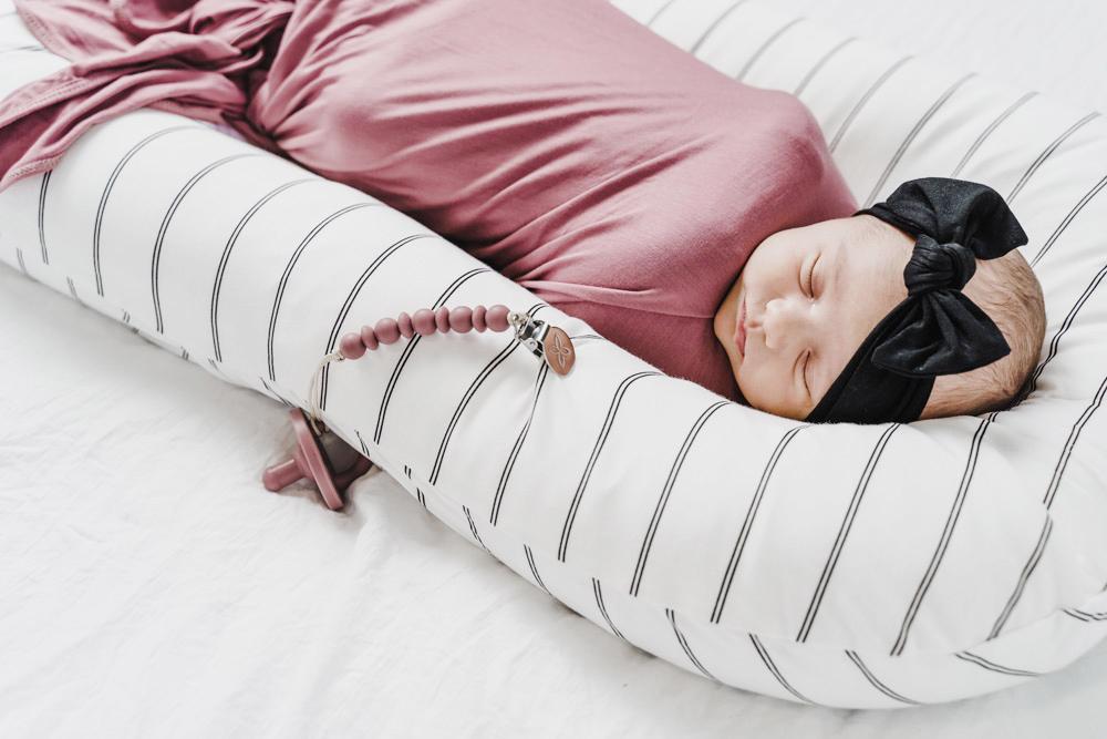 A cozy COCOON & COVER baby lounger in a soft color, featuring a removable liner and a custom-fit traveling case, designed for infants aged 0-36 months.