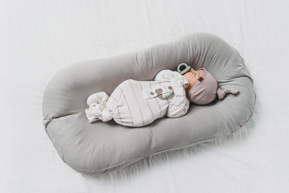 A cozy COCOON & COVER baby lounger in a soft color, featuring a removable liner and a custom-fit traveling case, designed for infants aged 0-36 months.