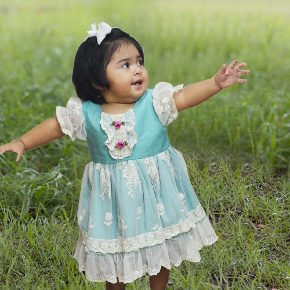 Harper Baby Dress in turquoise featuring ruffles, lace, and rosettes, perfect for infants.