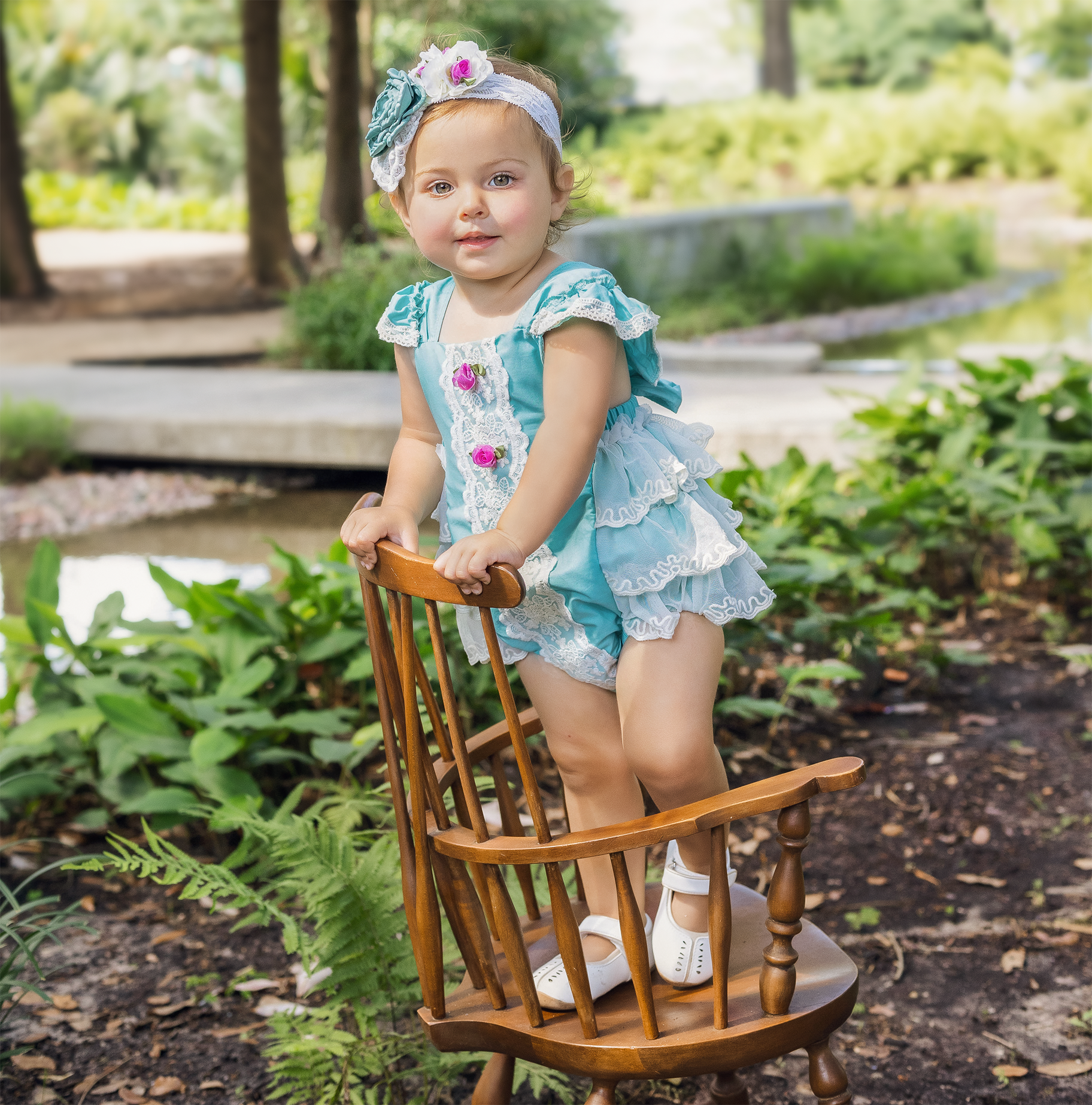 A beautiful turquoise sunsuit for girls featuring ruffles, lace, and rosettes, perfect for summer wear.