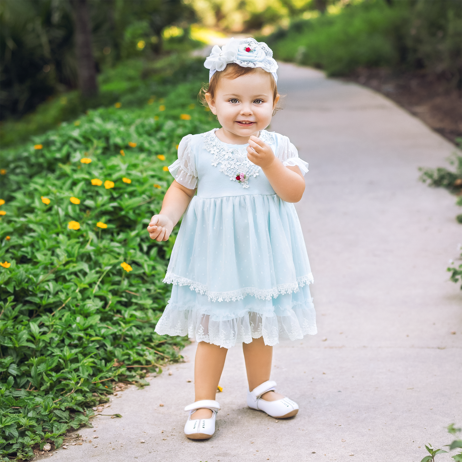 Pastel blue Iris Baby Dress featuring rosettes and a lace collar, perfect for young girls.