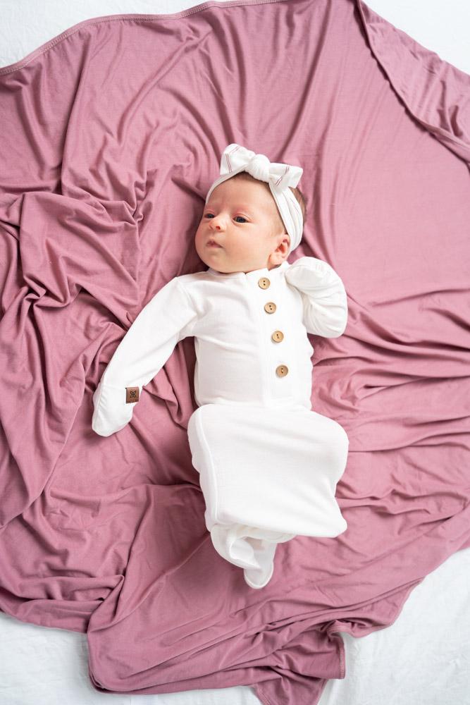 A soft and stylish knotted gown for babies, featuring functional buttons and a cozy design, perfect for diaper changes.