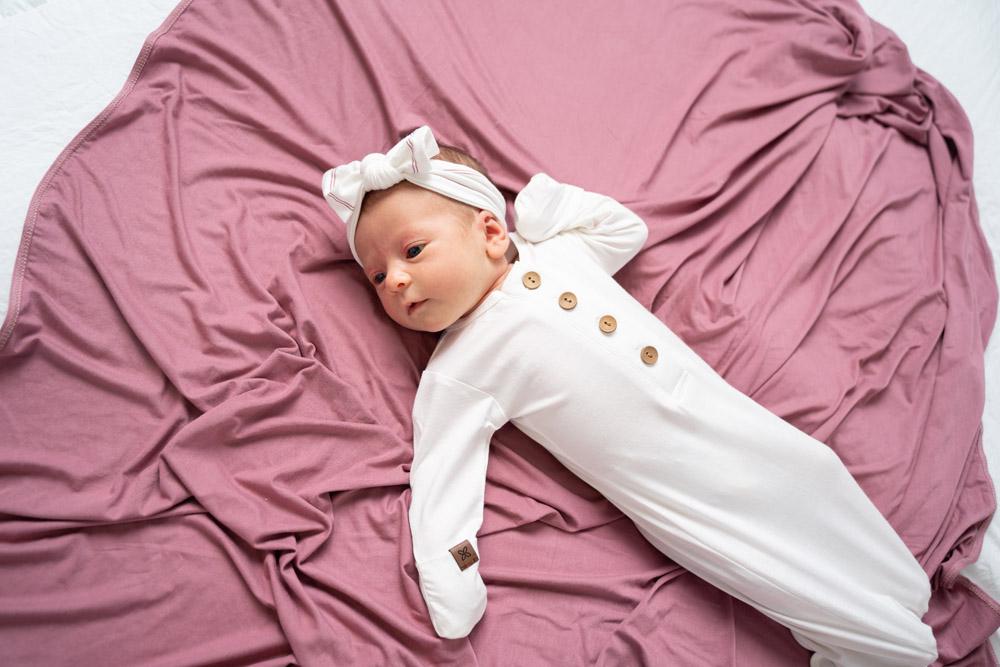 A soft and stylish knotted gown for babies, featuring functional buttons and a cozy design, perfect for diaper changes.