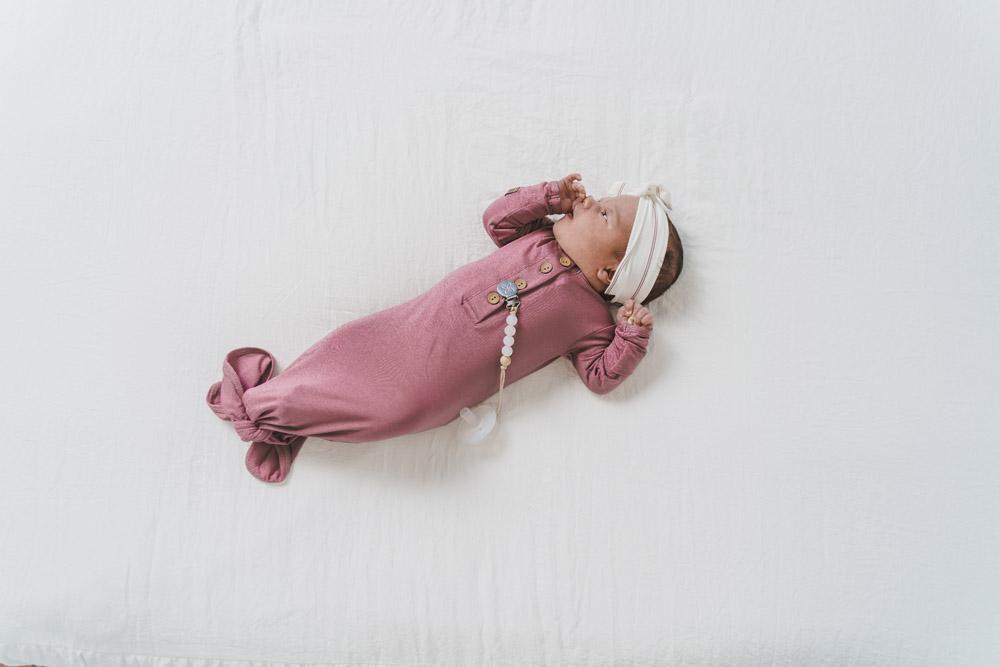 A soft and stylish knotted gown for babies, featuring functional buttons and a cozy design, perfect for diaper changes.