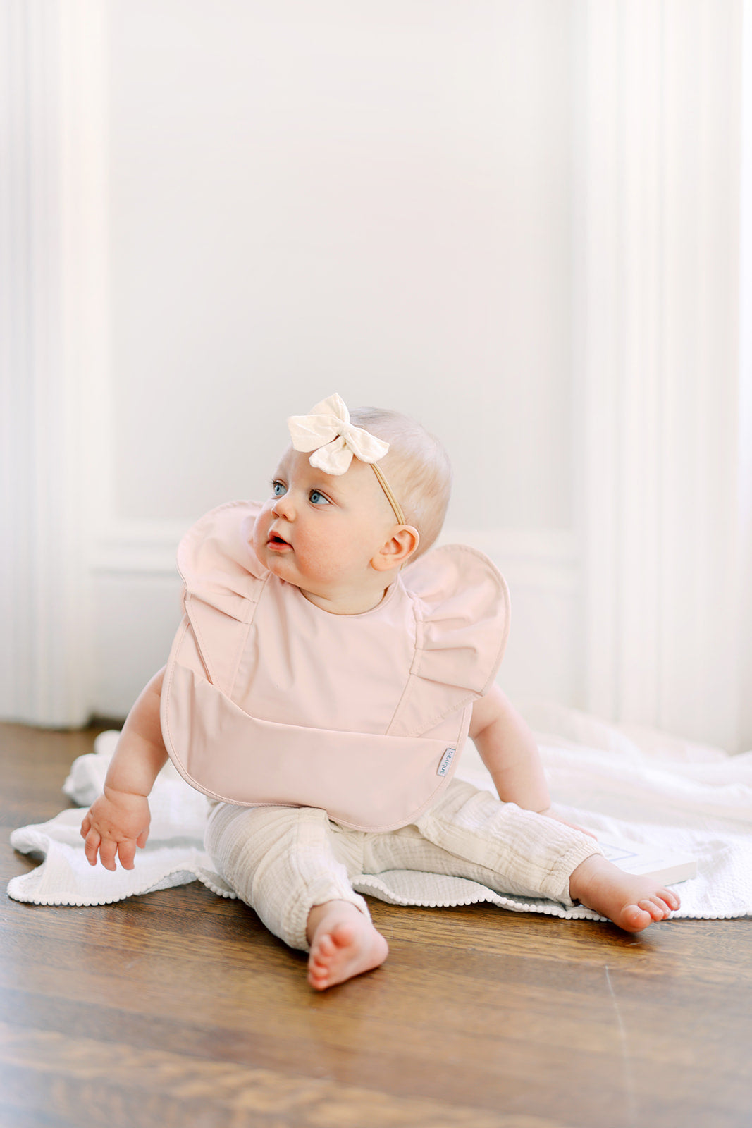 Peach Blush Ruffle Angel Bib showcasing its elegant design and practical features, perfect for baby mealtime.