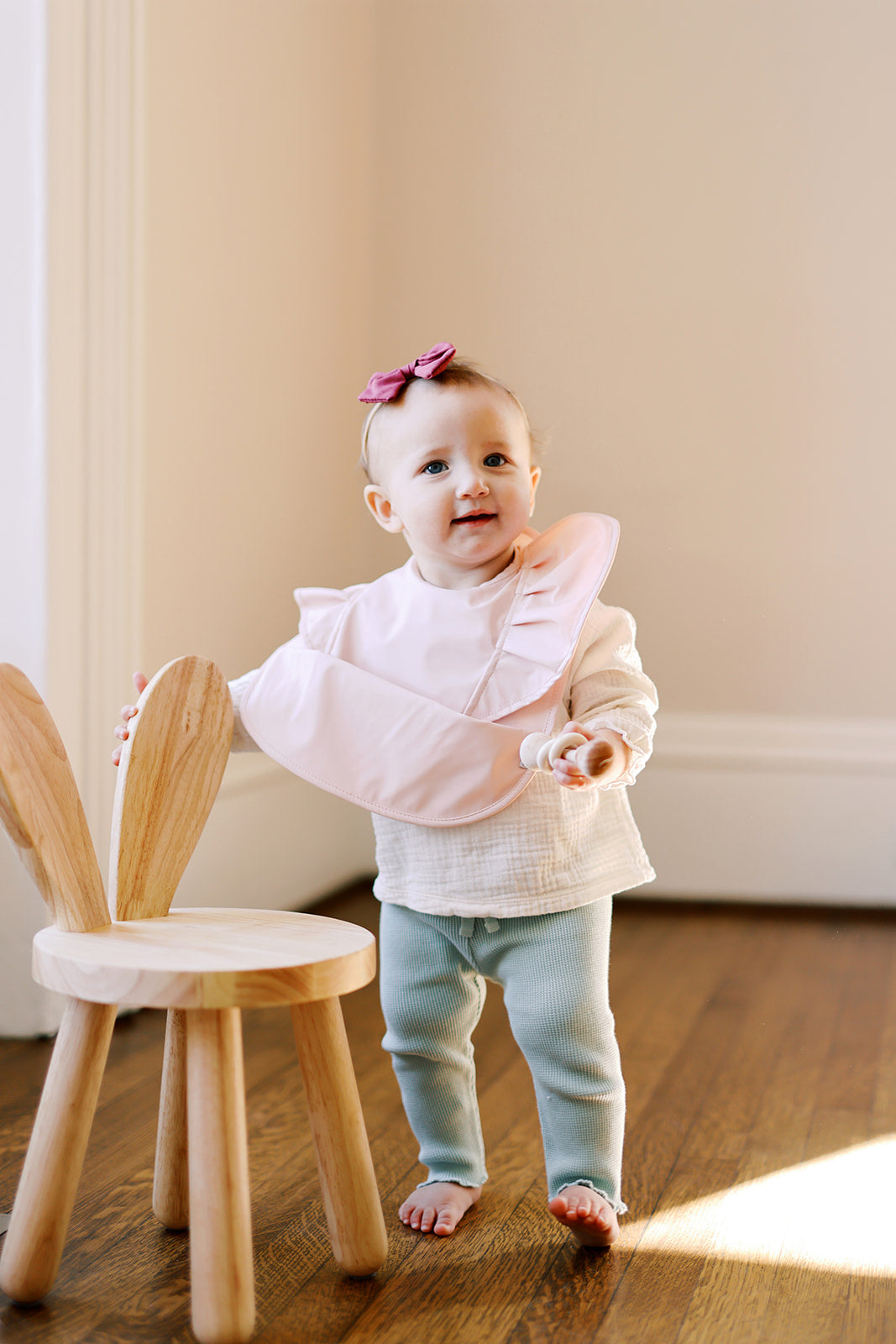 Peach Blush Ruffle Angel Bib showcasing its elegant design and practical features, perfect for baby mealtime.