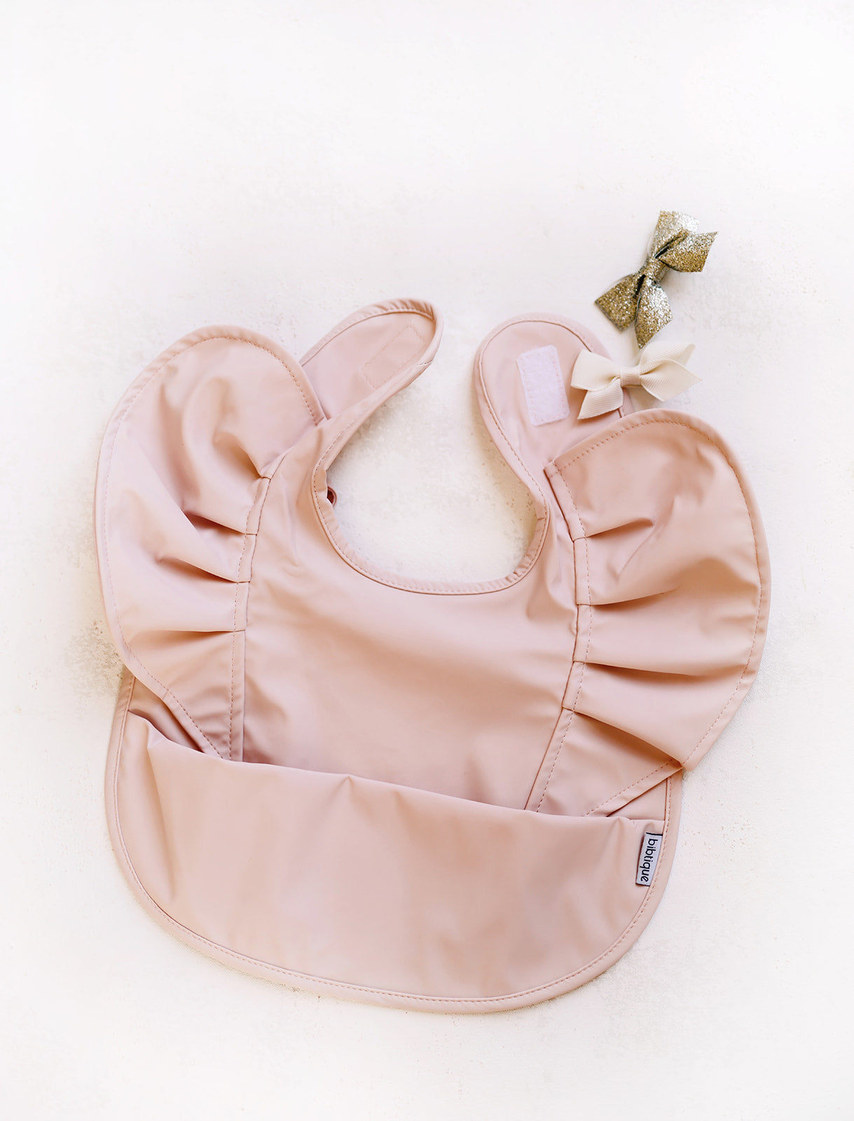 Peach Blush Ruffle Angel Bib showcasing its elegant design and practical features, perfect for baby mealtime.