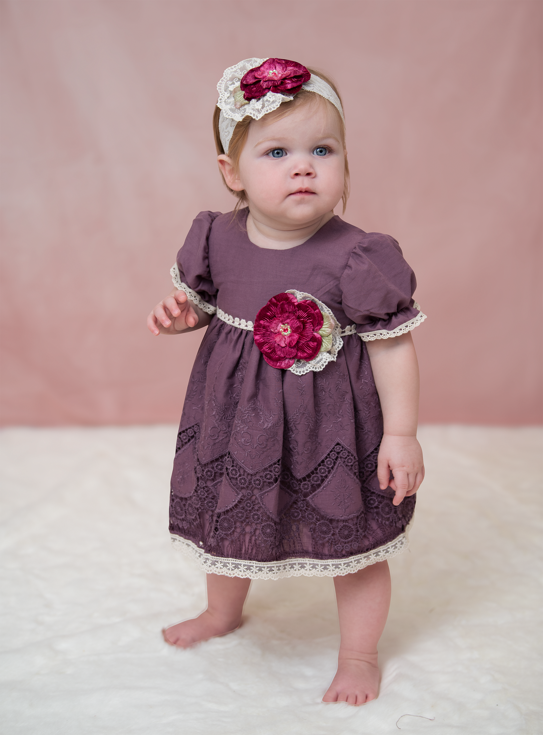 A beautiful Violet Field Baby Dress featuring intricate crocheted lace and rich purple fabric, perfect for special occasions.