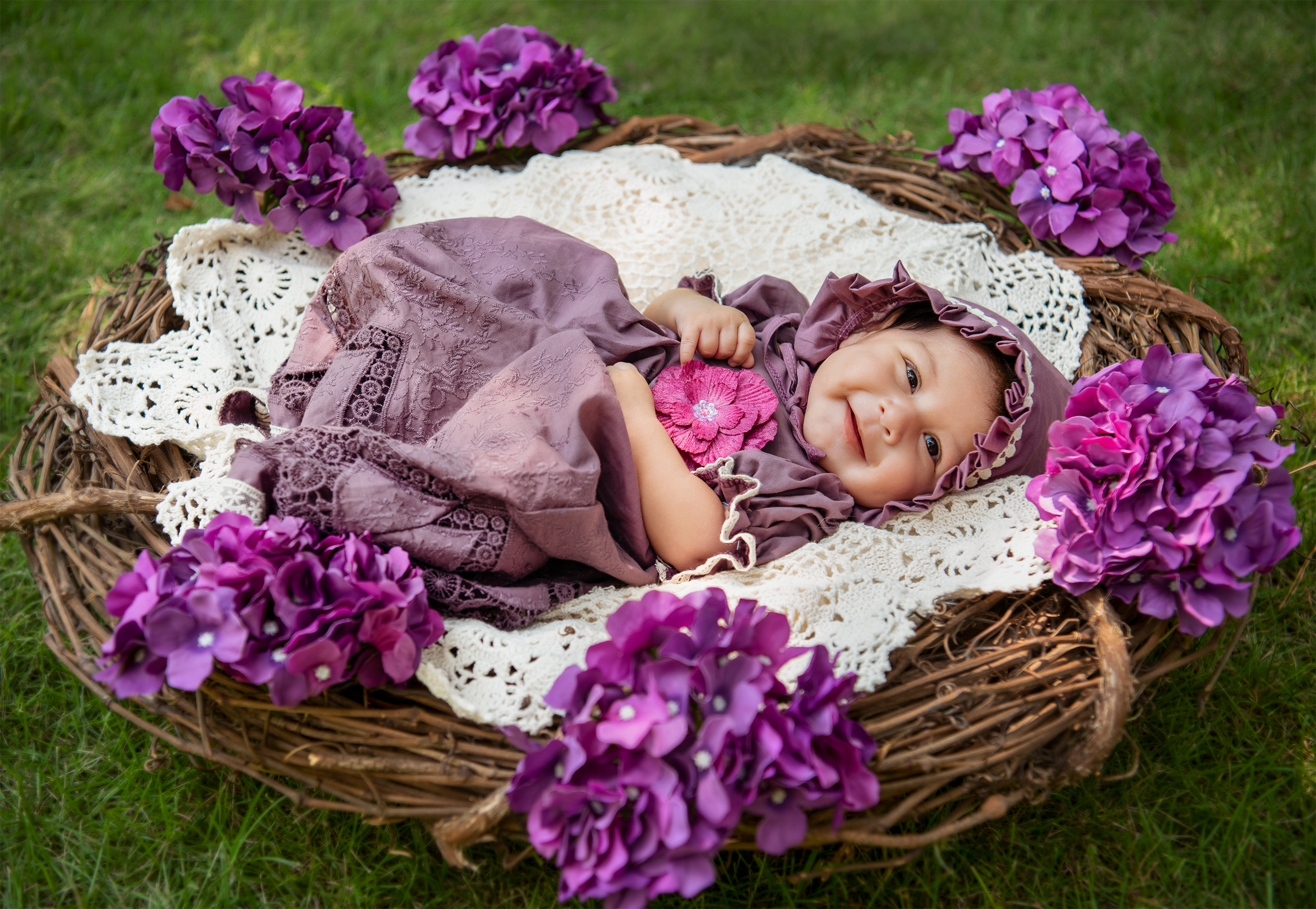 A beautiful baby gown in rich purple fabric with intricate crocheted lace detailing, perfect for special occasions.