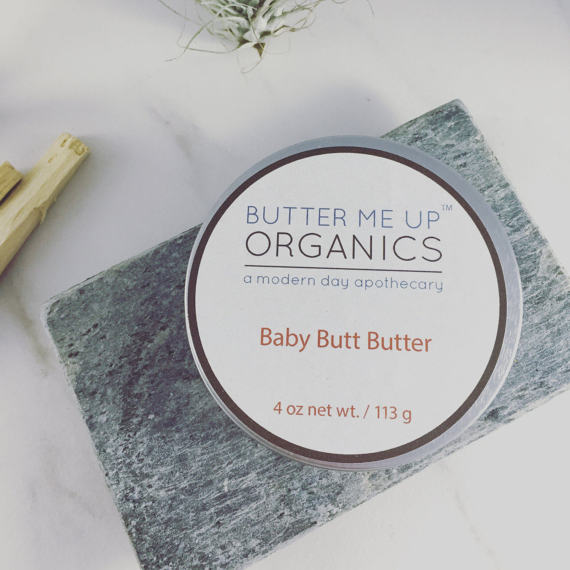 A 4oz tin of Baby Butt Butter, an organic diaper cream, featuring a creamy texture and natural ingredients like shea butter and coconut oil, ideal for soothing baby's skin.