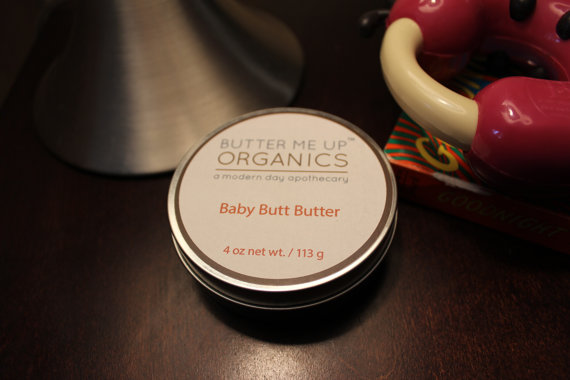 A 4oz tin of Baby Butt Butter, an organic diaper cream, featuring a creamy texture and natural ingredients like shea butter and coconut oil, ideal for soothing baby's skin.