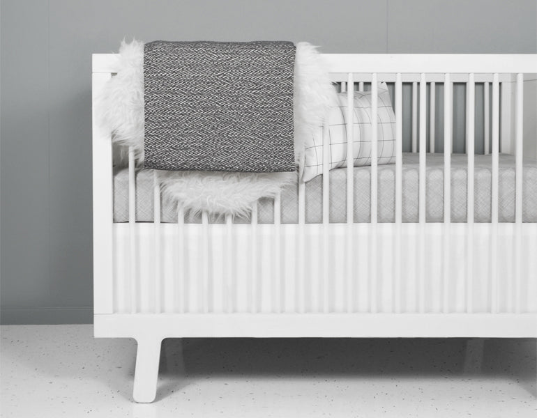 Avi Fitted Crib Sheet featuring modern neutral tones and sporadic lines, designed for a stylish nursery.