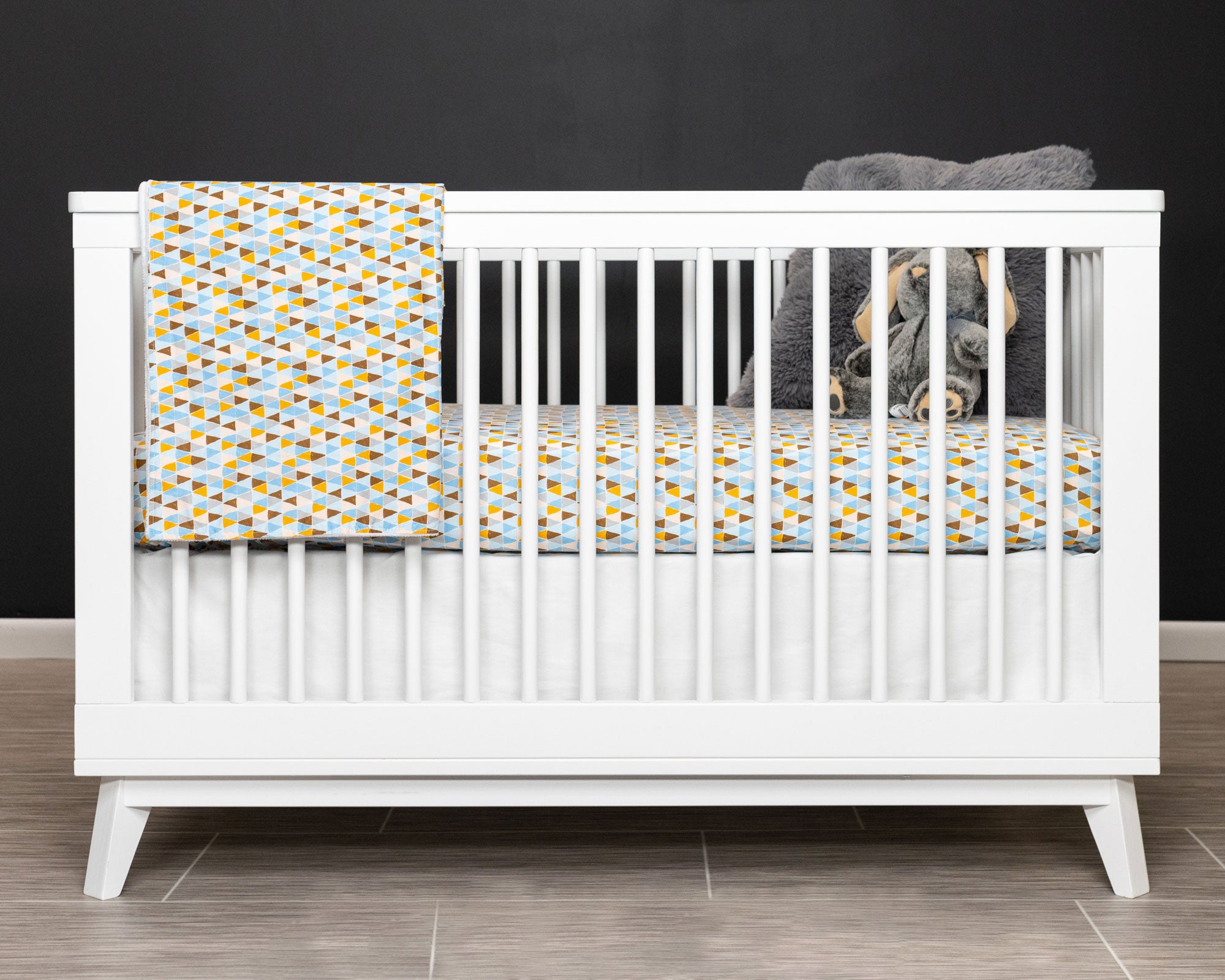 Blue Banners Marching Classic Crib Bedding Set featuring vibrant triangles in blue, brown, gray, and mustard colors, made from premium cotton.