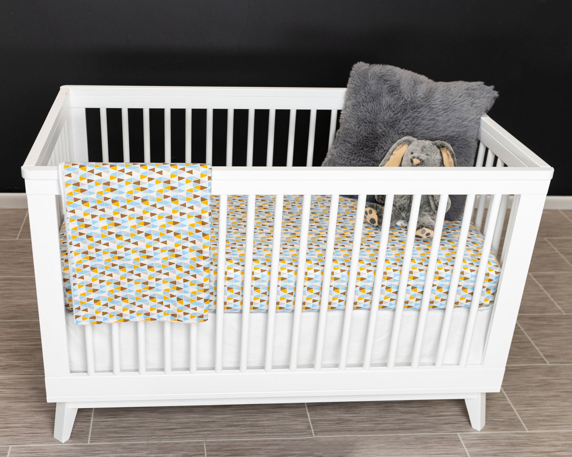 Blue Banners Marching Classic Crib Bedding Set featuring vibrant triangles in blue, brown, gray, and mustard colors, made from premium cotton.