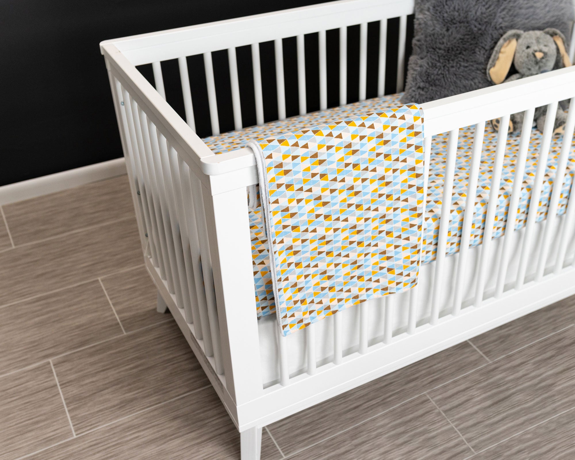 Blue Banners Marching Classic Crib Bedding Set featuring vibrant triangles in blue, brown, gray, and mustard colors, made from premium cotton.