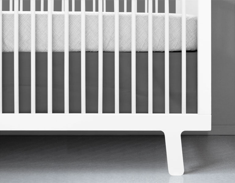 Stylish charcoal gray crib skirt tailored for standard cribs, made from heavyweight cotton twill.