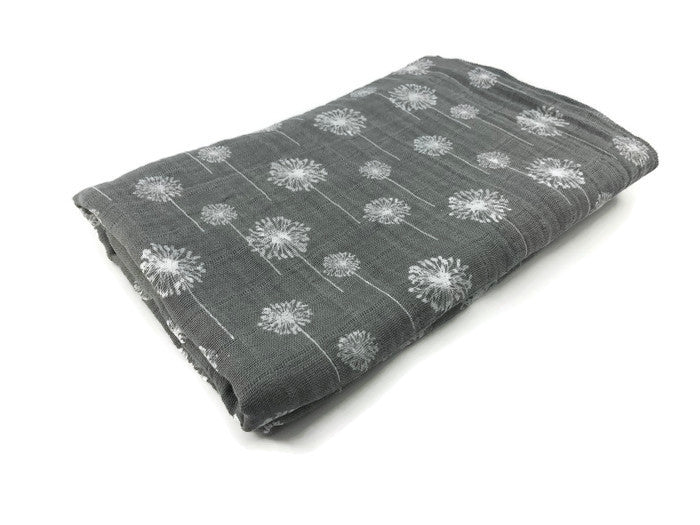 Dandelions Dance Swaddle Blanket featuring delicate floral patterns on soft cotton muslin fabric, perfect for modern nurseries.