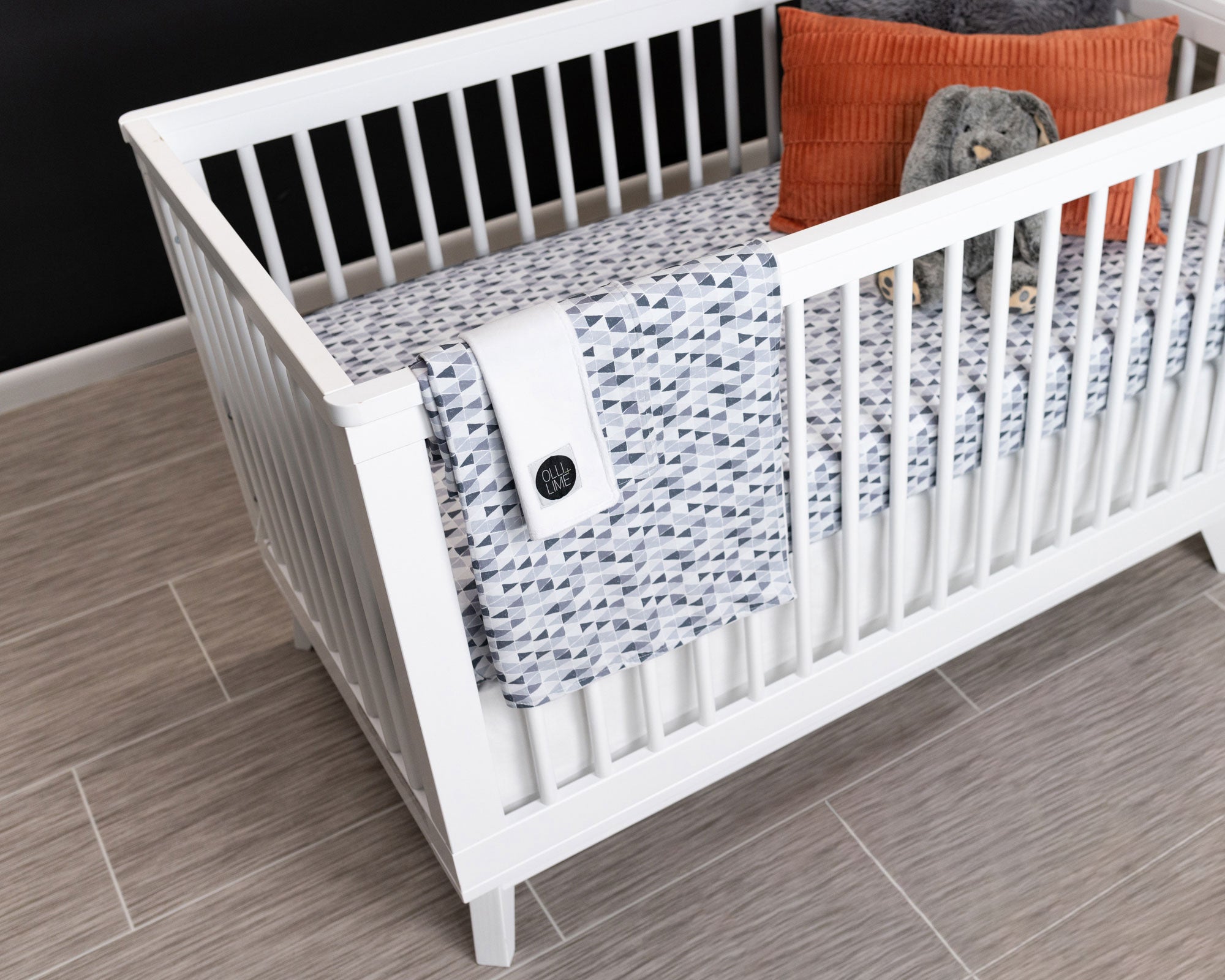 Gray Banners Marching Deluxe Crib Bedding Set featuring modern gray triangle patterns and soft cotton materials.