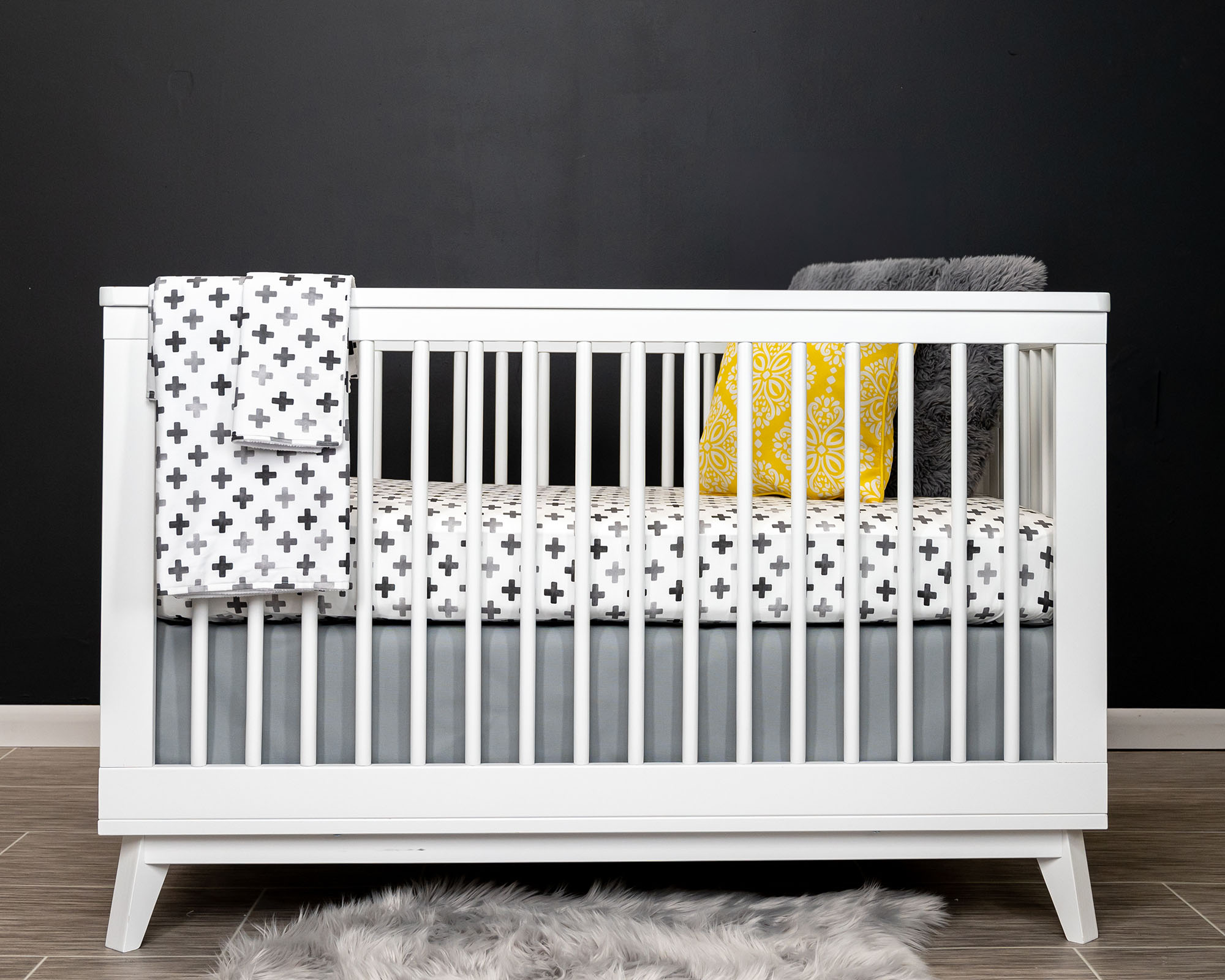 Hugo's Hazy Cross Deluxe Crib Bedding Set featuring gray Swiss cross pattern on white background, includes crib skirt, fitted sheet, baby blanket, and lovey.