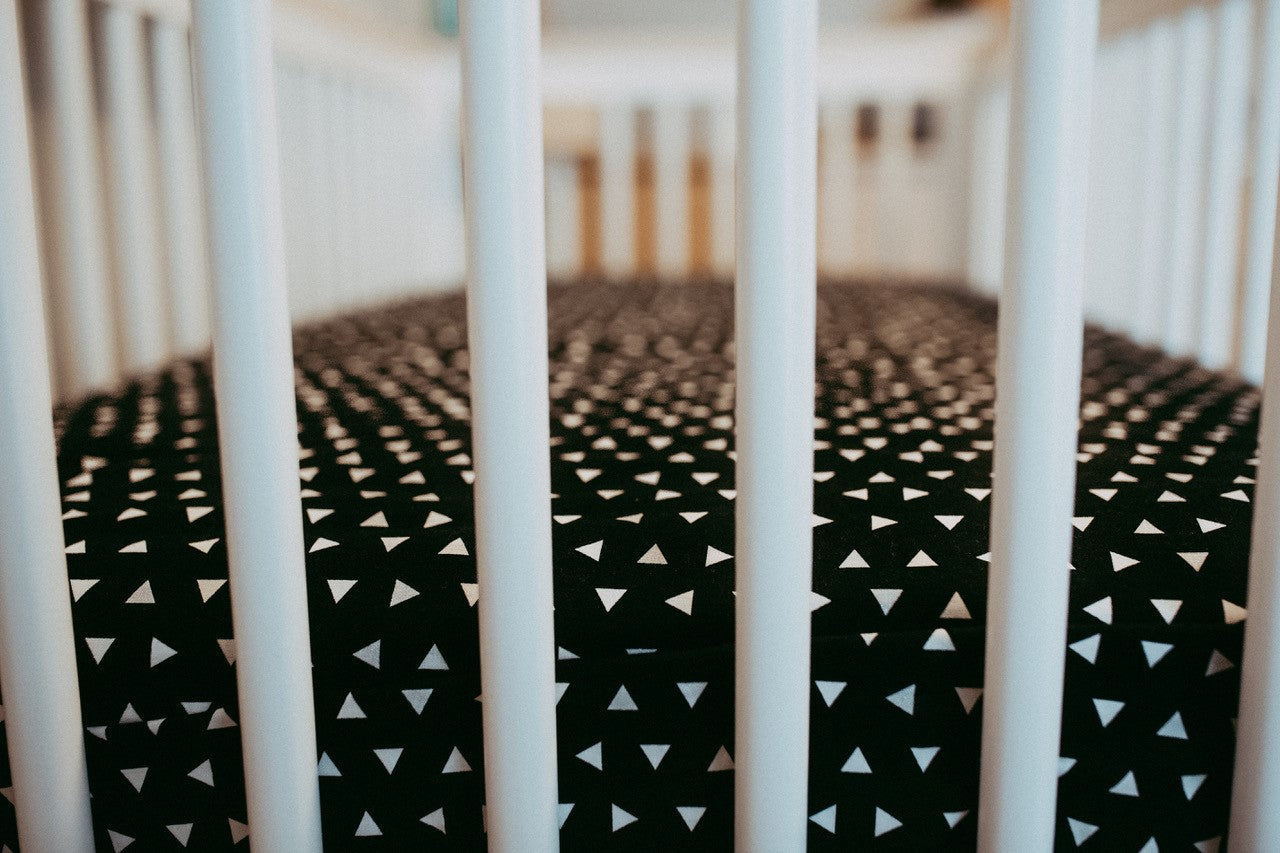 Kingsley Deluxe Crib Bedding Set featuring modern triangle designs in black and white with a grey weave blanket, perfect for stylish nurseries.