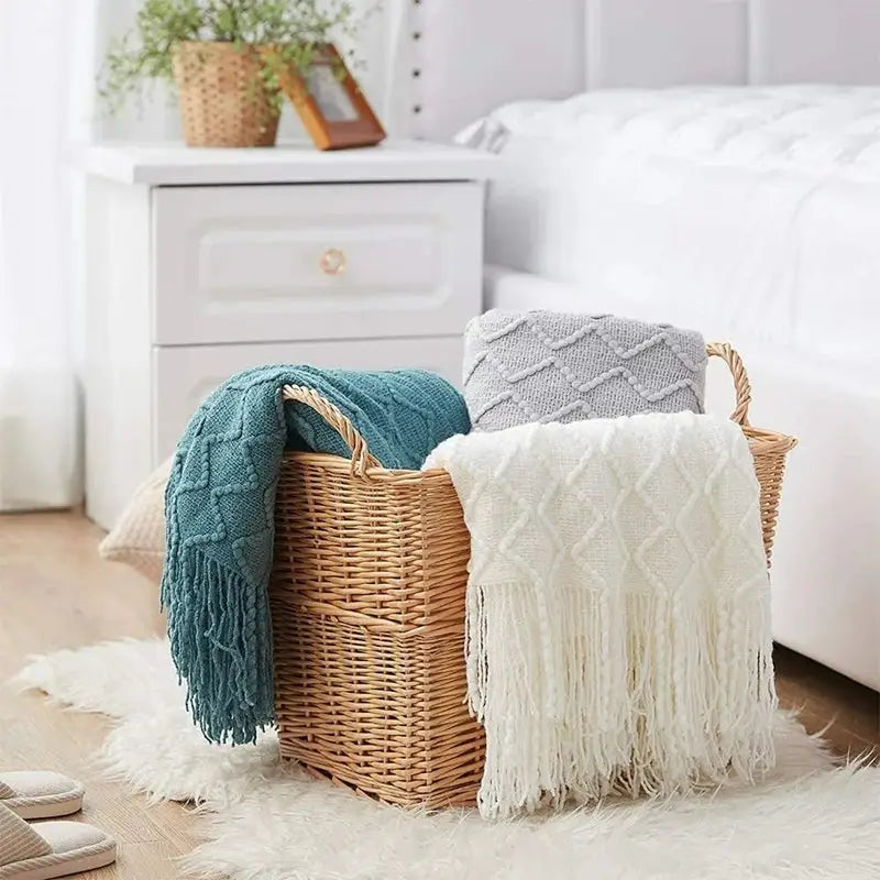 A beautifully knitted beige decorative blanket with geometric patterns and rolled fringed edges, showcasing its luxurious texture and craftsmanship.