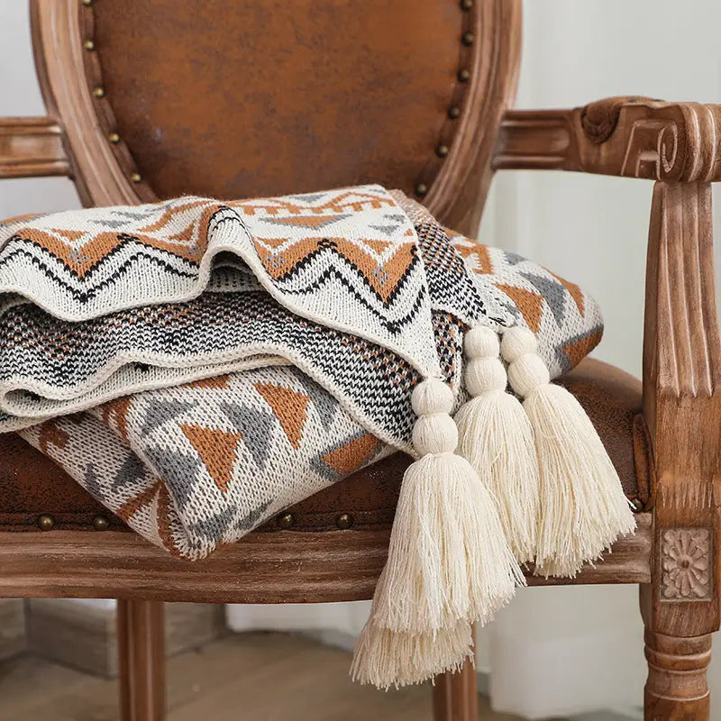 A luxurious knitted throw blanket featuring an intricate geometric pattern, made from high-quality cotton, perfect for home decor.