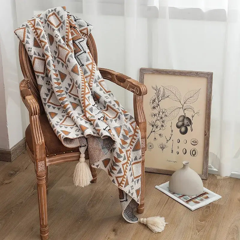 A luxurious knitted throw blanket featuring an intricate geometric pattern, made from high-quality cotton, perfect for home decor.