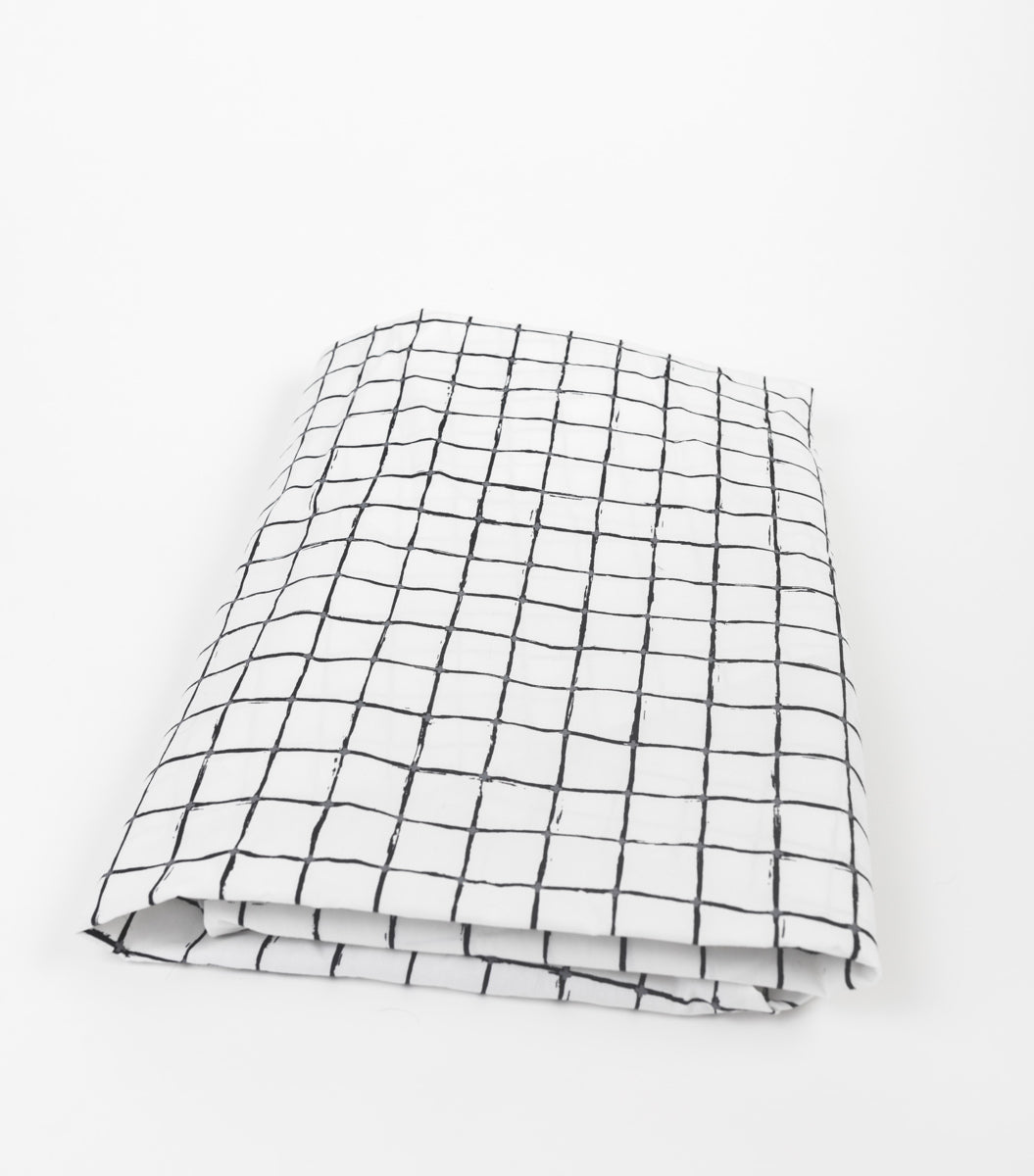 Luca Fitted Crib Sheet featuring a modern loose black grid pattern on soft cotton percale fabric, designed for standard cribs.