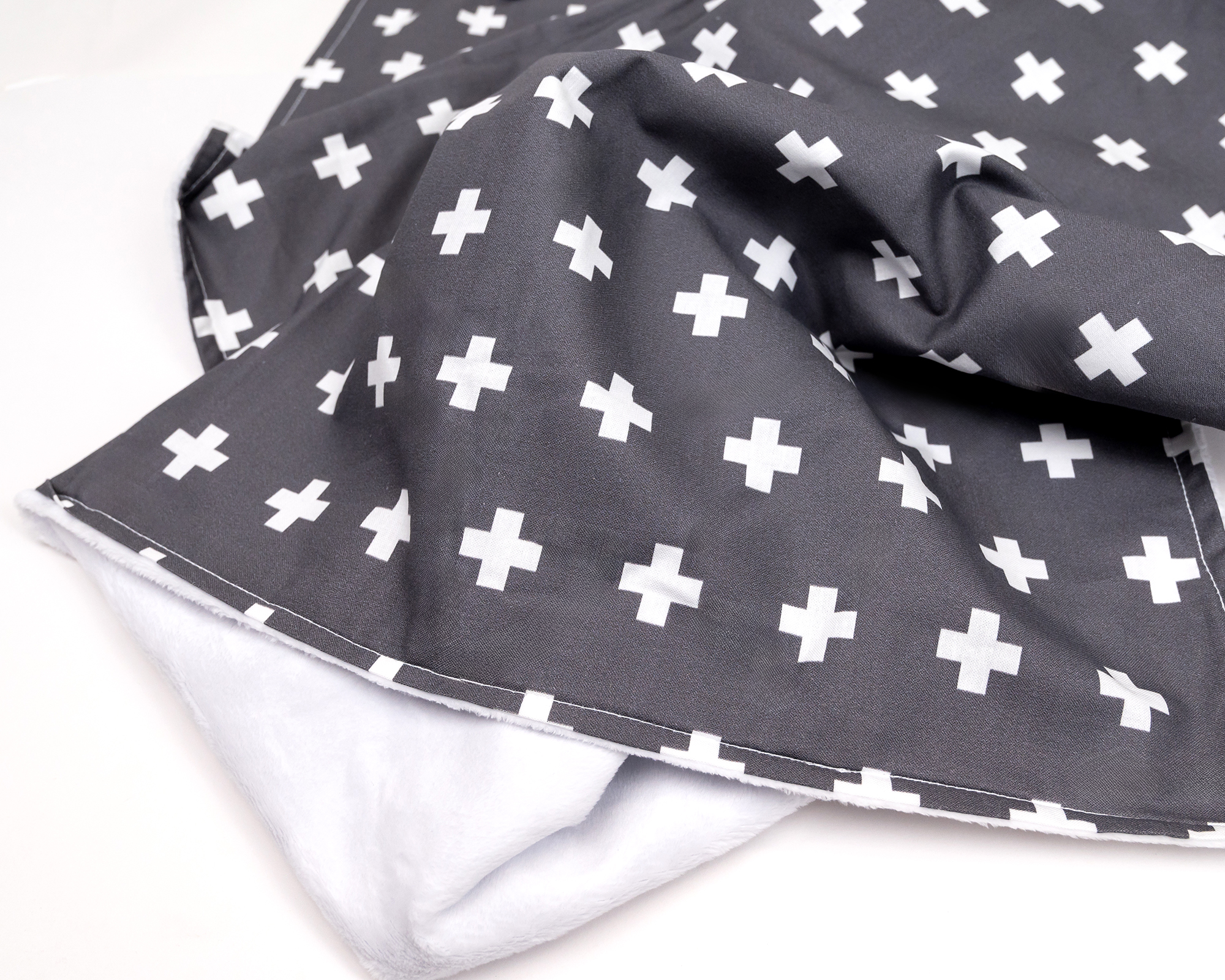 Nils Baby Blanket featuring a white Swiss cross pattern on a dark gray background, made from premium cotton.