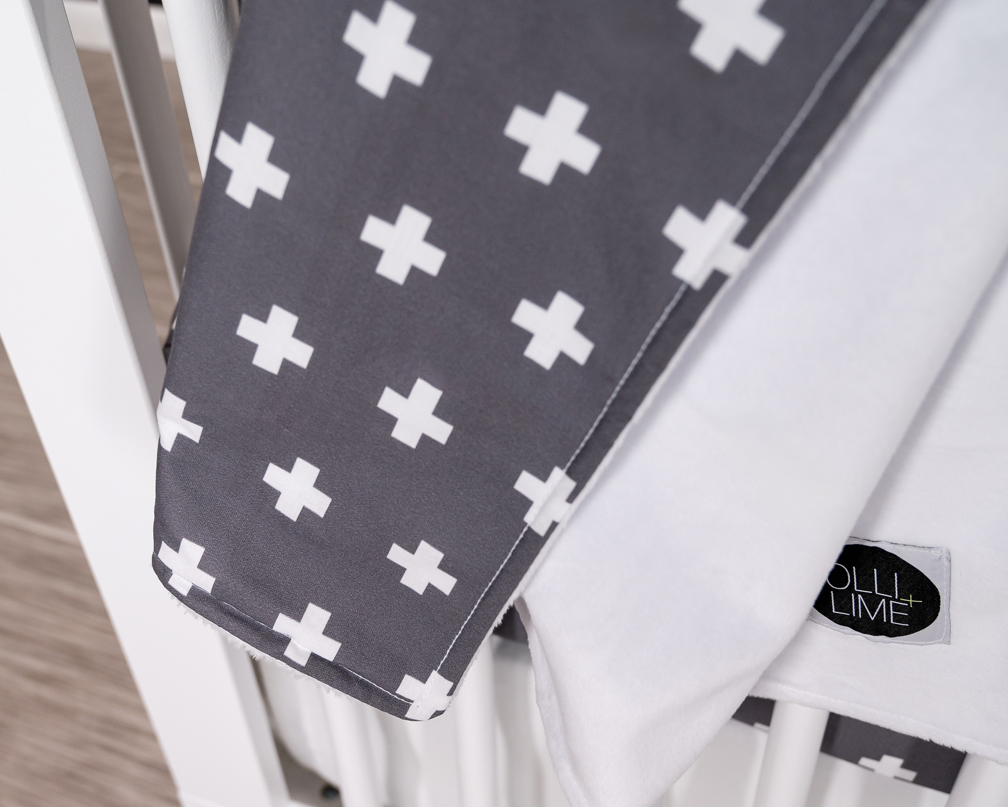 Nils Baby Blanket featuring a white Swiss cross pattern on a dark gray background, made from premium cotton.