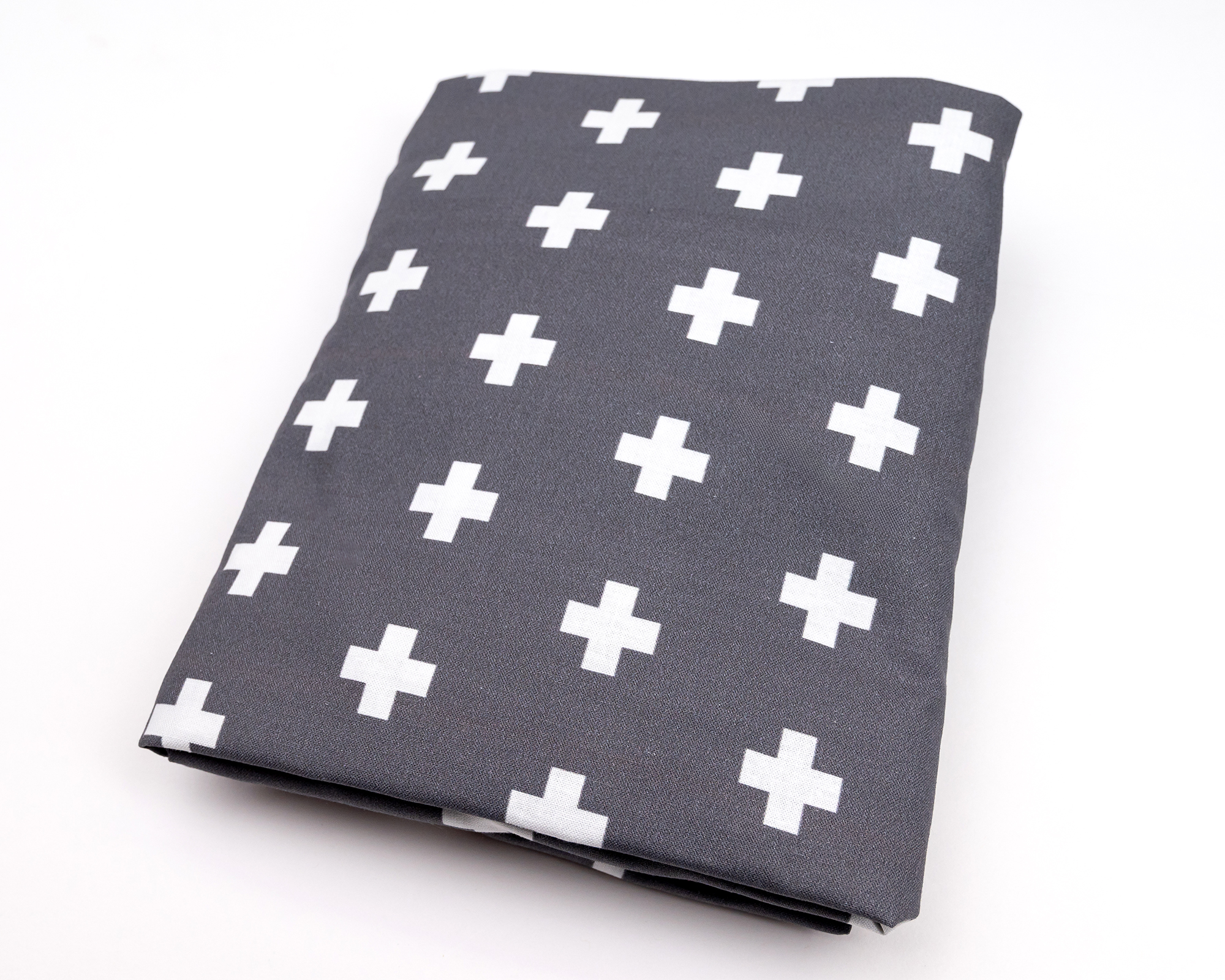 Nils Fitted Crib Sheet featuring a stylish white Swiss cross pattern on dark gray fabric, designed for modern nurseries.