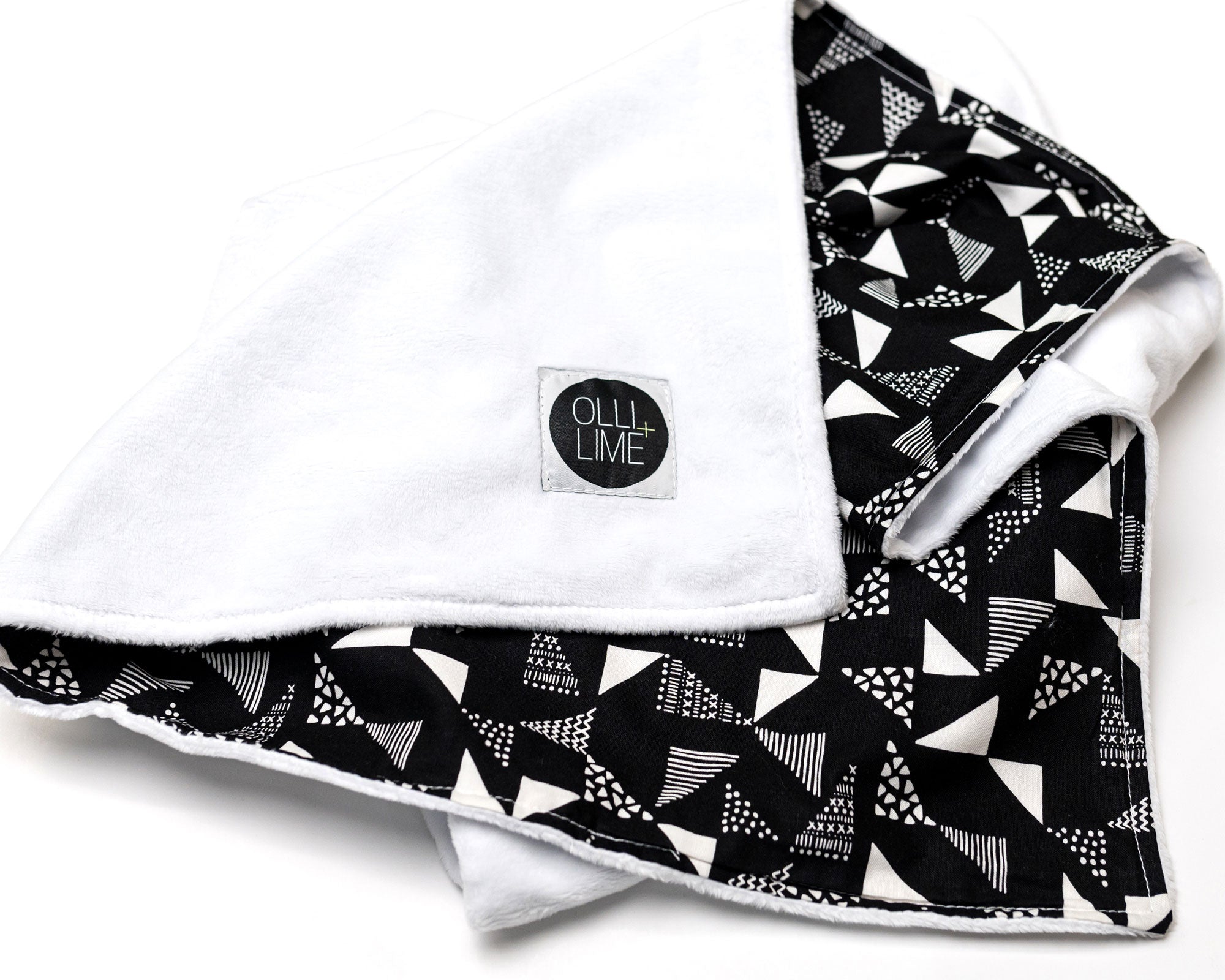 Pinwheels Crib Bedding Set featuring modern triangle patterns in gray and white on a black background, including a crib skirt, fitted sheet, and baby blanket.