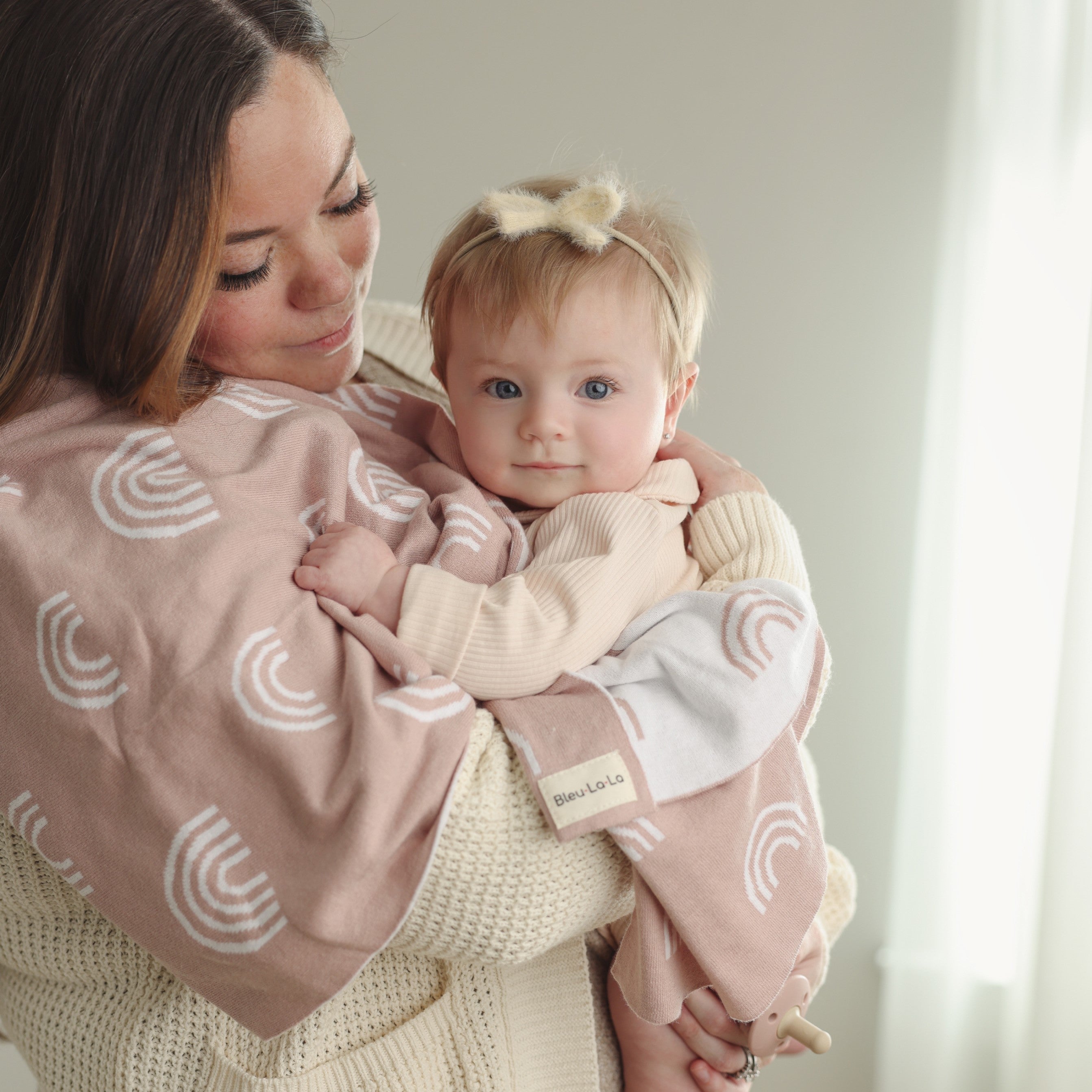 A colorful rainbow knit swaddle blanket made of soft cotton, perfect for wrapping newborns and toddlers, featuring a gentle and breathable design.