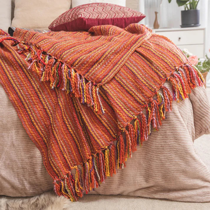 A cozy Varigated Tassel Throw featuring colorful patterns and tassels, perfect for home decor.