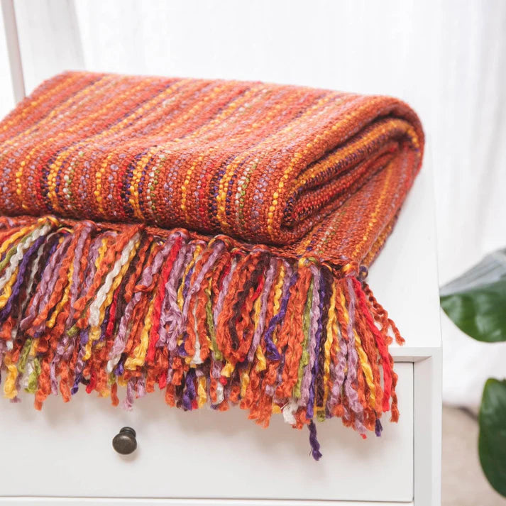 A cozy Varigated Tassel Throw featuring colorful patterns and tassels, perfect for home decor.