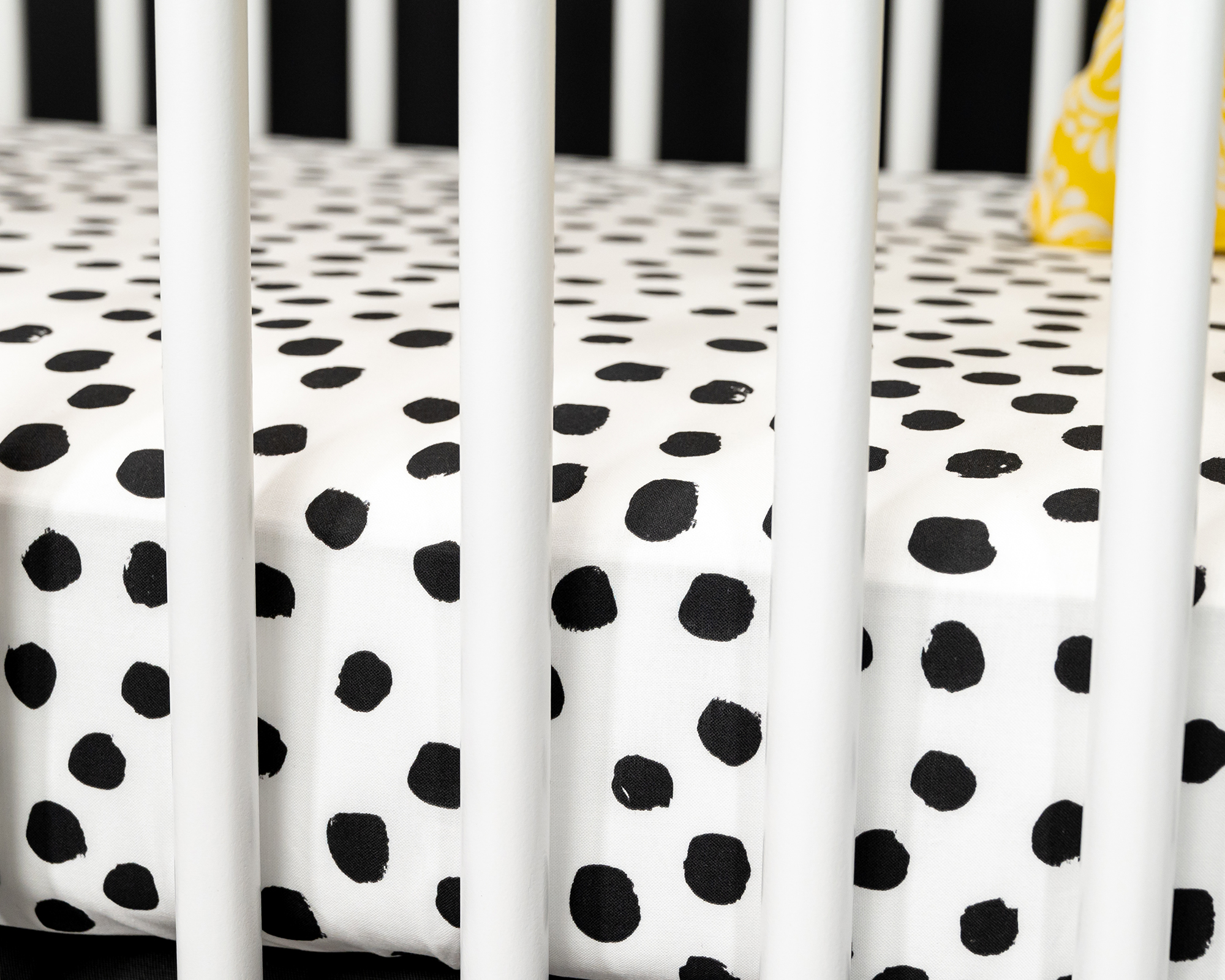 Zoe's Spots & Dots Fitted Crib Sheet featuring a modern black-on-white polkadot design, made from 100% premium cotton.