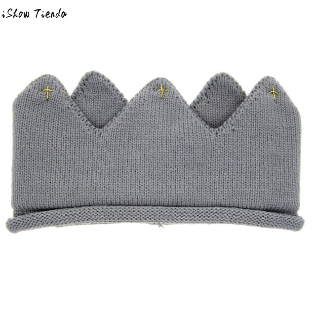 A cute baby wearing a knitted crown-shaped hat, showcasing a soft cotton material in a playful cartoon pattern, perfect for newborns and toddlers.