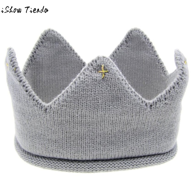 A cute baby wearing a knitted crown-shaped hat, showcasing a soft cotton material in a playful cartoon pattern, perfect for newborns and toddlers.